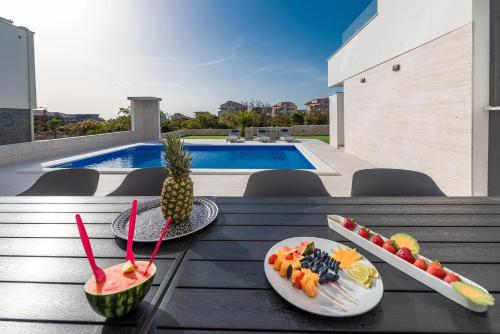 诺瓦利娅Apartments & Rooms Pool Villas Maris的一张桌子,上面放有果盘和 ⁇ 萝