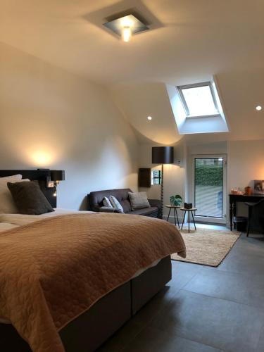 哈弗尔特B&B Otterstee的一间卧室配有一张床、一张沙发和天窗。