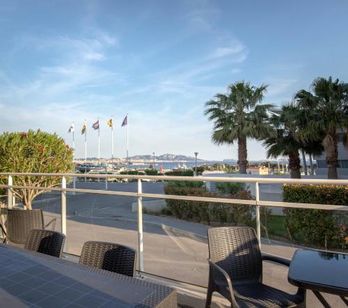 马赛马赛埃斯塔克宜必思快捷酒店的阳台配有桌椅和棕榈树。