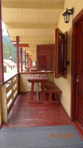 红湖Casutele Likas的门廊配有木制野餐桌和窗户