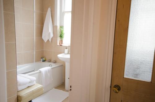 布莱顿霍夫Seaview Mansion Apartment - Central Hove with PARKING的浴室配有白色浴缸、盥洗盆和浴缸。