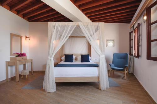 林都斯Thea Villas and Suite的一间卧室配有天蓬床和蓝椅