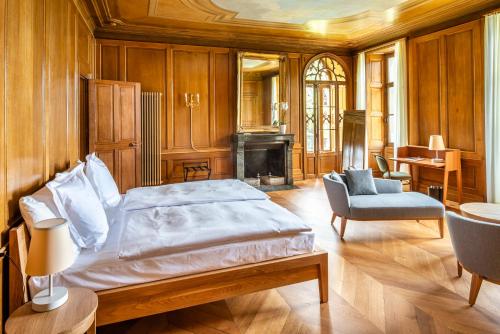 图恩Schloss Schadau - Swiss Historic Hotel的一间卧室配有一张床、一把椅子和一个壁炉