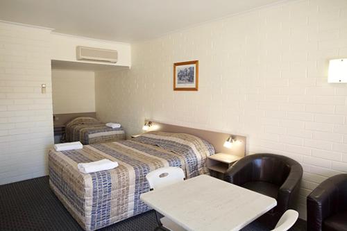 贡迪温迪Pioneer Motel Goondiwindi的酒店客房带两张床和一张桌子以及椅子。