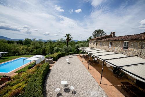 卢卡Accogliente alloggio con vista e piscina的一座带桌子和遮阳伞的户外庭院毗邻一座建筑