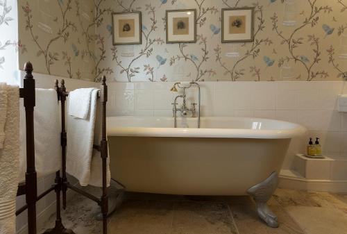 隆霍斯雷Thistleyhaugh farmhouse的浴室设有白色浴缸,配有壁纸