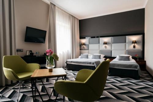 克拉科夫阿派斯酒店的酒店客房带两张床和一张桌子以及椅子。