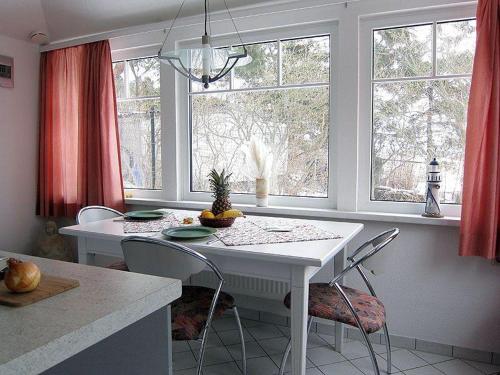 Klein ZickerUns Gartenhus的厨房配有白色的桌子、椅子和窗户。