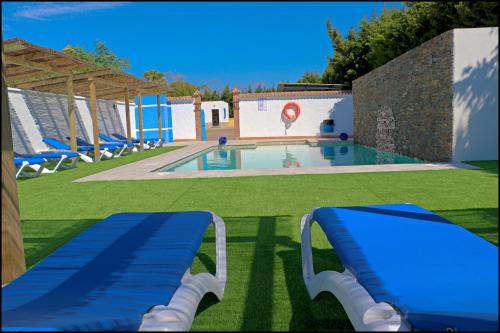 科尼尔-德拉弗龙特拉Bungalow La Roa IV的一个带蓝色椅子的游泳池和一个游泳池