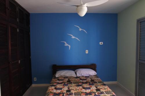 卡拉瓜塔图巴Apto praia Martim de Sá的一间卧室,墙上有鸟儿画的蓝色墙壁