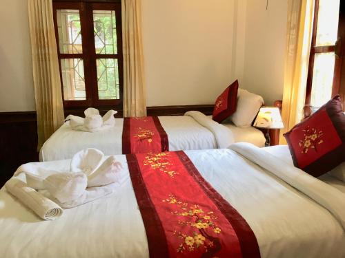 琅勃拉邦维拉凡宫旅馆的酒店客房,配有三张床和毛巾