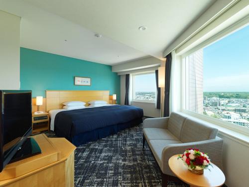 札幌札幌艾米西亚酒店的酒店客房配有床、沙发和电视。