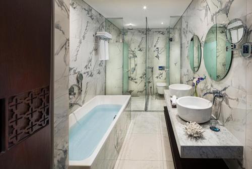 迪拜Millennium Place Dubai Marina的浴室配有2个盥洗盆、浴缸和镜子