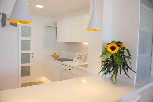 卡内·德·玛尔Apartamento frente al mar的白色的厨房,带花瓶,内有向日葵