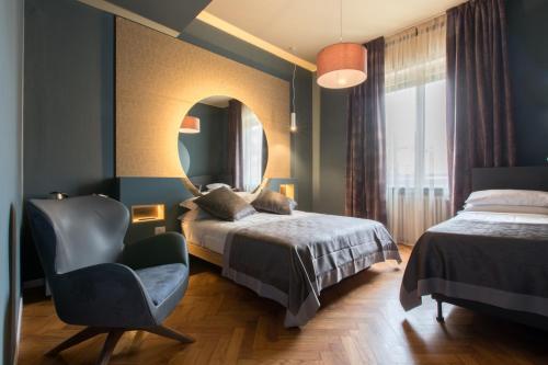 米兰Le Texture Premium Rooms Duomo-Cordusio的一间卧室配有一张床、一把椅子和镜子