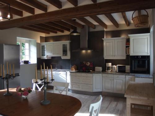 PouancéAu calme dans la campagne du Haut Anjou的厨房配有白色橱柜和木桌