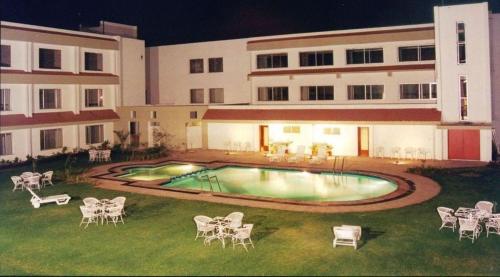 SikaHotel Express Residency-Jamnagar的夜间在建筑物的院子中的一个游泳池