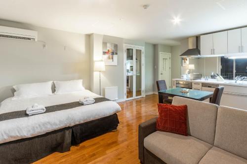 富良野新鲜的粉末公寓式酒店的一间卧室配有一张床和一张沙发,还设有一间厨房