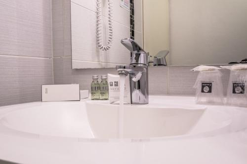 尚贝里尚贝里中心艾拓酒店的浴室水槽设有水龙头和镜子