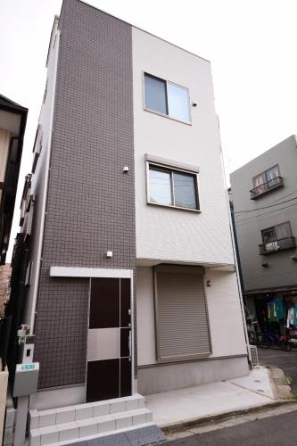 东京QiQi House Tokyo まるごと新築一軒家宿 Spacious New Home, 8 Guests, Easy Airport & Disney Access的街道上设有门窗的建筑