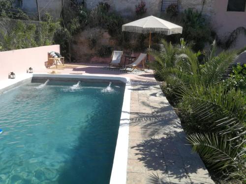 ZujairaLa Casa Grande de Zujaira的一个带遮阳伞的庭院内的游泳池