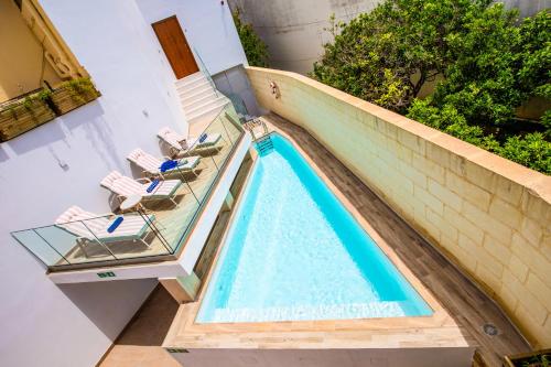SiġġiewiPjazza Suites Boutique Hotel by CX Collection的一个带2把躺椅的游泳池和一个游泳池