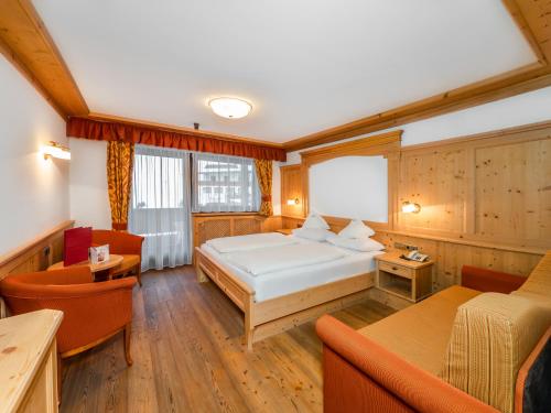 塞尔瓦迪加尔代纳山谷阿拉斯加酒店的一间卧室,卧室内配有一张床和椅子