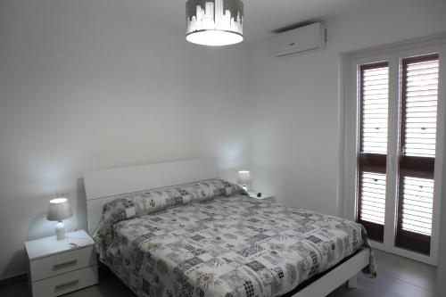 拉古萨Casa Felice的白色卧室配有一张床和一个吊灯
