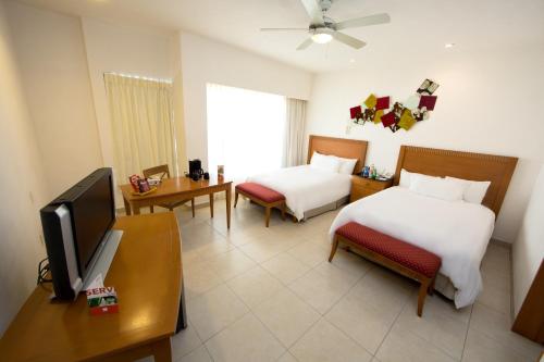 坎昆亲密套房酒店的酒店客房设有两张床和电视。