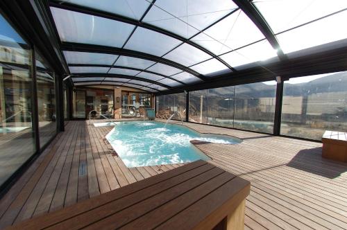 Las Cuevas de CañartAparthotel SPA Don Iñigo de Aragón的甲板上设有玻璃屋顶的游泳池