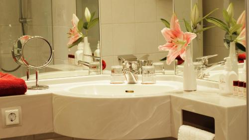 黑尔福德Hotel zur Fürstabtei的浴室配有带镜子的盥洗盆和粉红色的鲜花