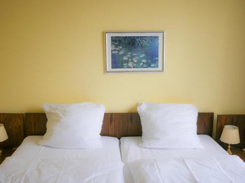 科布伦茨Hotel Oronto的两张带白色床单的床和一张墙上的照片