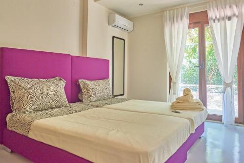 罗达奇诺Pura Vida的一张大床,在房间内有一个紫色床头板