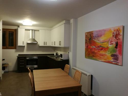 普埃尔托德尔松Apartamento en Primera Linea的厨房配有木桌和墙上的绘画作品