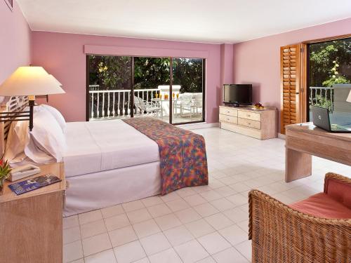 吉拉尔多特托卡勒玛酒店的一间卧室配有一张床、一台电视和一个阳台
