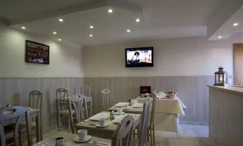 鲁瑟拉勒璨多尔酒店的一间带桌椅的餐厅以及墙上的电视
