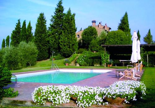 皮恩扎Le Traverse的一个带遮阳伞和一些白色花卉的游泳池