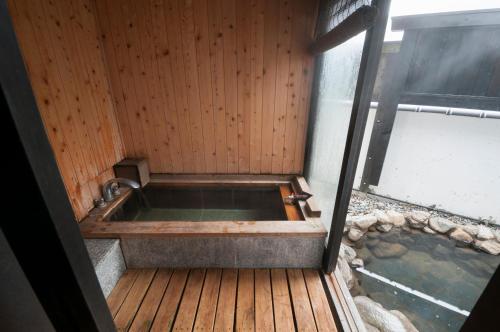 高山冈田日式旅馆和乐亭的木甲板上的浴缸,有水体