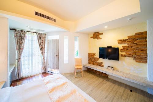垦丁大街萌香渡假旅店的客厅设有壁挂式平面电视。