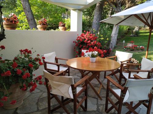 撒尼海滩Sani Villa Maria的庭院里种着鲜花,配有木桌和椅子