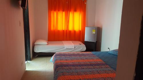 托卢cabañas Juakianna的客房设有两张床和一个带橙色窗帘的窗户。