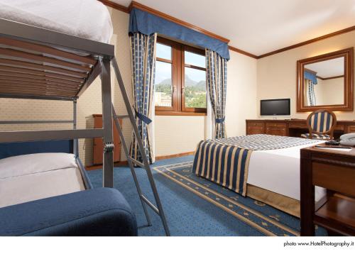 特伦托特兰托大酒店的配有双层床和书桌的酒店客房