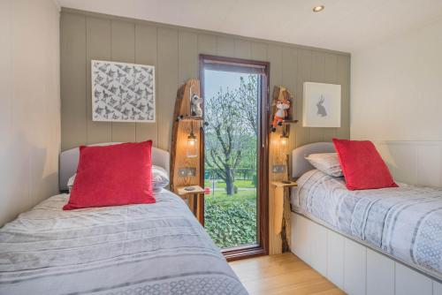 巴森斯韦特Dobby Lodge的带窗户的客房内的两张床和红色枕头