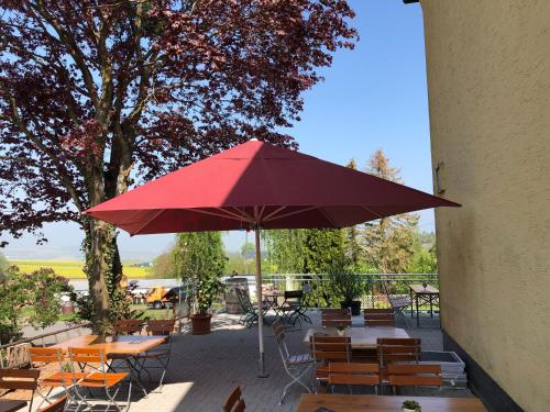 维尔舍姆Landhaus vor Burg Eltz的一个带桌椅和红色遮阳伞的庭院