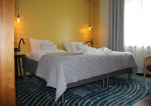 尼奈斯港尼纳斯哈伍斯百德酒店的卧室内的一张床位,卧室的墙壁为黄色