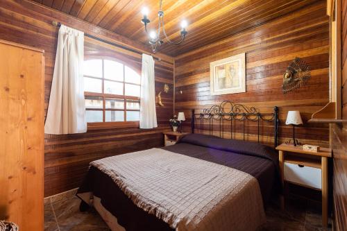 圣巴托洛梅Camping Cabin - Private Solarium & Pool - BBQ的卧室设有木墙、一张床和窗户