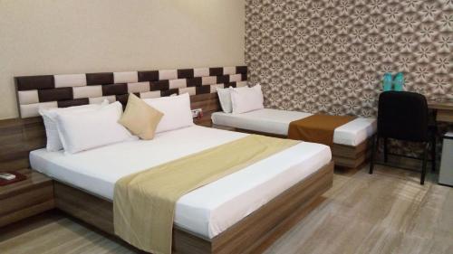 NavsāriHotel Shahi Darbar的酒店客房,配有两张床和椅子