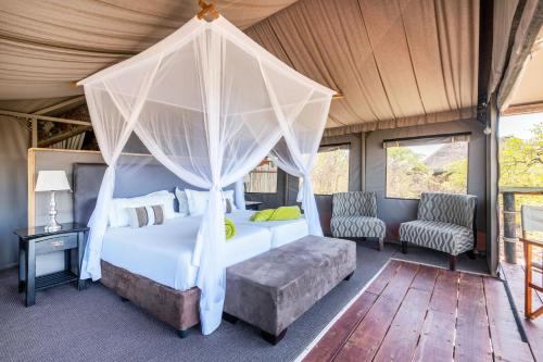 奥考奎约Eagle Tented Lodge & Spa的一间卧室配有一张天蓬床和两把椅子