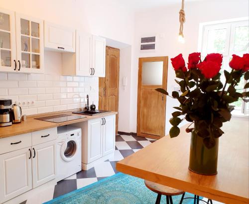 克拉科夫Topolove Rooms & Apartments的厨房配有一张带玫瑰花瓶的桌子
