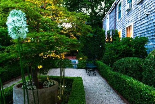 楠塔基特Union Street Inn的一座花园,花园内有树和长凳,一座建筑